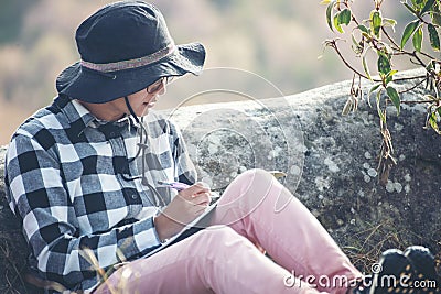 Traveller make note holiday trip on notebook. Asian Woman write and plan daily appointment schedule in diary. Planner mark and Stock Photo