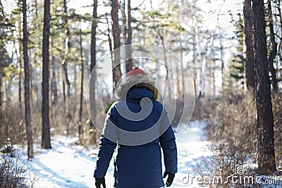 Traveller man in a blue winter jacket ad red cap in the woods. Sandy bay, Baikal lake, winter time Stock Photo