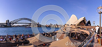 Travellers and local people have drink and enjoy sunny day at Opera bar in front of The Opera House, with a beautiful clear blue Editorial Stock Photo