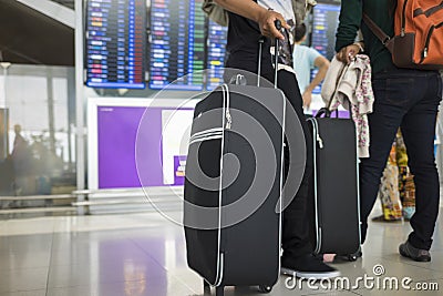 Travelling suitcase against flight information board on background. Concept of travel by airplane Stock Photo