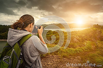 Travelling woman photographer with backpack making an inspiring Stock Photo