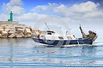 Trawler fishing boats in arrival to lighthouse in Spain. Editorial Stock Photo