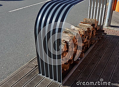 Tray of chopped firewood. arched frame of corrugated gray sheet metal on a wooden terrace. The roof is covered with snow and rain Stock Photo