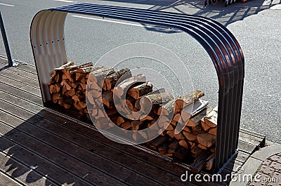 Tray of chopped firewood. arched frame of corrugated gray sheet metal on a wooden terrace. The roof is covered with snow and rain Stock Photo