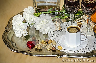 Tray of nickel silver with a bouquet of carnations, black coffee,old crystal glasses and a bottle of liquor Stock Photo