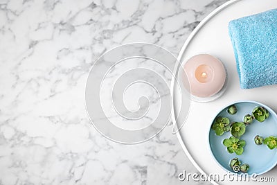 Tray with towel, candle, bowl of water and flowers on marble table. Space for text Stock Photo