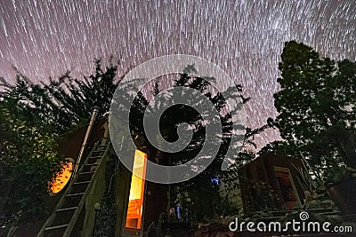 wood sauna in the middle of nature under a circular spiral stars trail Stock Photo