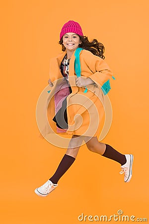 Tread on air. Active small child rush to school on yellow background. Happy girl enjoy active lifestyle. Little Stock Photo