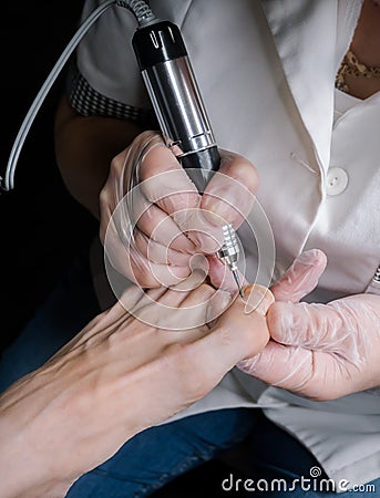 Treatment of the cuticle cutter on the nails of the feet. Stock Photo
