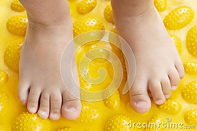 Treatment and prevention of flat feet in children. A small child walks barefoot on an orthopedic mat puzzle. Stock Photo