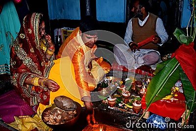 Treditional worshipping of god performing by an Indian Family. The family bearing an Indian dress in suffron colour. Editorial Stock Photo
