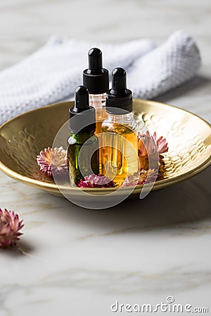 Tree bottles of natural organic beauty face oil serum for cosmetic anti age treatment skin care with towel, gold metal bowl, dried Stock Photo