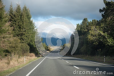 Tree lined road leading to the mountains Stock Photo