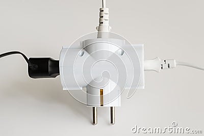 Tree plugs socketed into white electric splitter on a white background. Splitter for simultaneous switching of three electrical Stock Photo