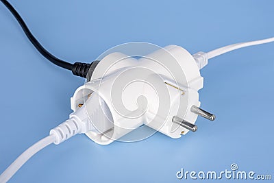 Tree plugs socketed into white electric splitter on a blue background. Splitter for simultaneous switching of three electrical Stock Photo