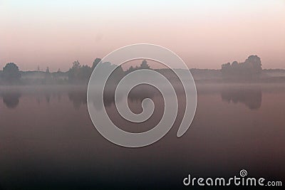 Magnificent summer nature on a pond in July. Trees, field and pond in the rays of the setting sun. Stock Photo