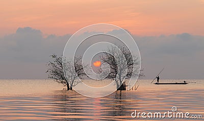 Trees and fisherman in the lake with beautiful sunrise and sky. Stock Photo