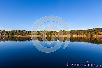 Trees reflecting in calm river water. Stock Photo