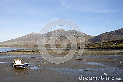 Lone small fishing boat at a deserted beach at Trefor, near Caernarfon, North Wales Stock Photo