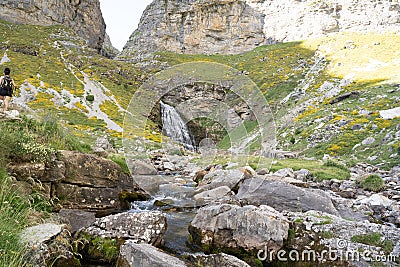 trekker woman and her dog approaching a river waterfall in Ordesa National Park, in the Spanish Pyrenees Stock Photo