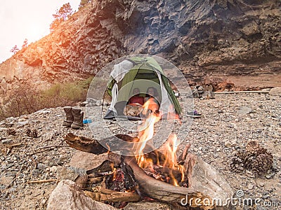 Trekkers couple inside tent camping in rock mountains with their dog - Sporty people relaxing after a trekking day next fire. Stock Photo
