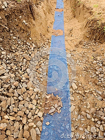 Trench with blue plastic protection tape. Marked of cables under clay during building of internet Stock Photo