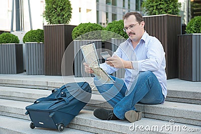 Trendy adult man in the town with touristic map outdoors. Stock Photo
