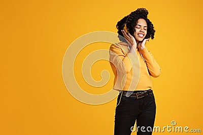 Trendy african american young woman with bright smile dressed in casual clothes and headphones clothing listening music Stock Photo