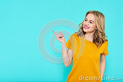 Trendy attractive young woman wearing mustard color summer dress posing over pastel blue background. Front view of smiling woman. Stock Photo