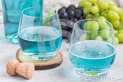 Trendy blue moscato wine in glass and in bottle, green and red grape on background, horizontal Stock Photo