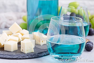 Trendy blue moscato wine in a glass served with a cheese plate, green and red grape on background, horizontal Stock Photo