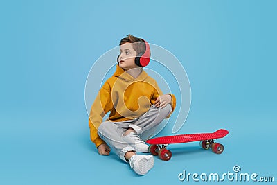 Stylish youngster listening to music near longboard Stock Photo