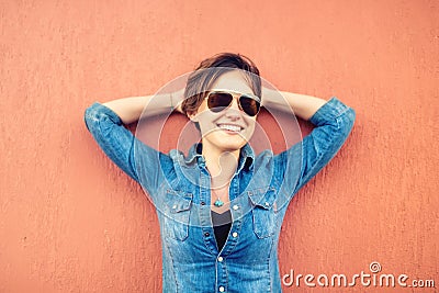 Trendy brunette girl, making face expressions, smiling and laughing against orange background, isolated. Modern lifestyle Stock Photo