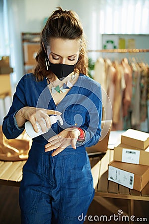 Trendy business owner woman disinfecting hands in office Stock Photo