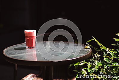 Trendy drink, red berry coffee latte with foam on transparent table in the street cafe Stock Photo