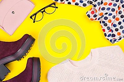 Trendy female autumn clothing. Stylish purple suede ankle boots, pink sweater, purse, glasses and printed scarf Stock Photo