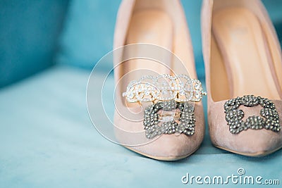 Trendy, graceful suede high heel shoes and wedding rings and jewelery in a blue suede chair. Wedding details. Stock Photo