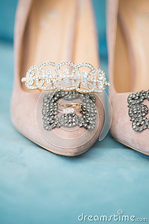 Trendy, graceful suede high heel shoes and wedding rings and jewelery in a blue suede chair. Wedding details. Stock Photo