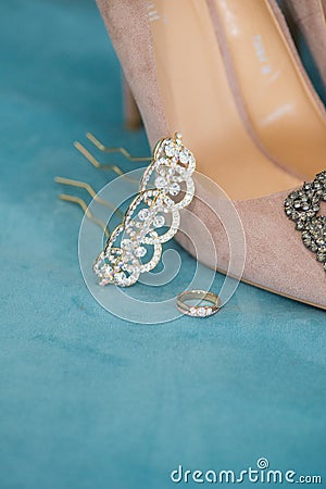 Trendy, graceful suede high heel shoes and wedding rings and jewelery in a blue suede chair. Wedding details. Stock Photo