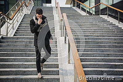 Trendy handsome young man in winter fashion standing on a long staircase Stock Photo