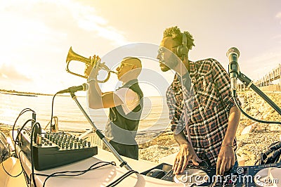 Trendy hipster dj playing summer hits at sunset beach party Stock Photo