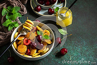 Trendy home breakfast. Mini pancakes, honey and cherries Stock Photo