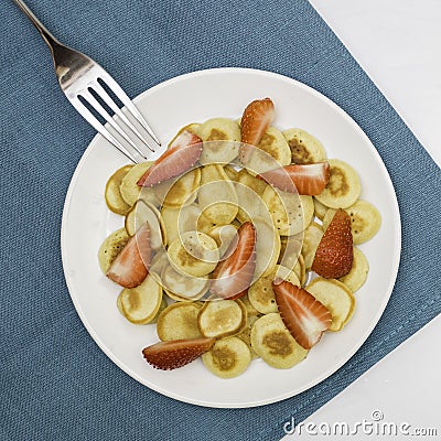 Trendy home breakfast with tiny pancakes, bananas and strawberry on a colored towel. View from above. Stock Photo