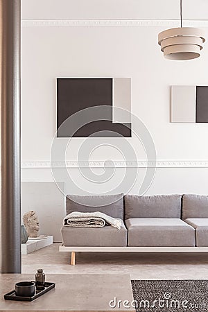 Trendy living room interior with white wall, painting and grey settee Stock Photo