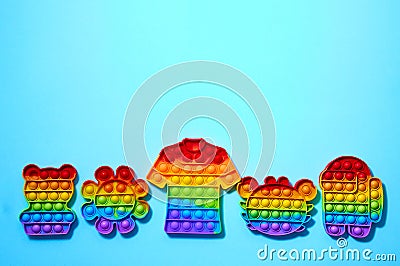 Trendy pop it toys in form of t-shirt, crab, bear, flower, and a character among us on blue background. Stock Photo