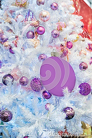 Trendy purple, ultraviolet colored baubles on silver white artificial Christmas tree. Close up. Selective focus, copy space. Stock Photo