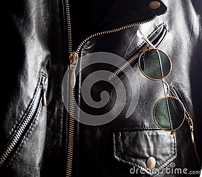 Trendy vintage circle sunglasses in a pocket of a studded jacket Stock Photo