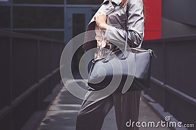 Trendy woman in silver pants jacket with black bag in hand street look. Fashionable outfit Stock Photo