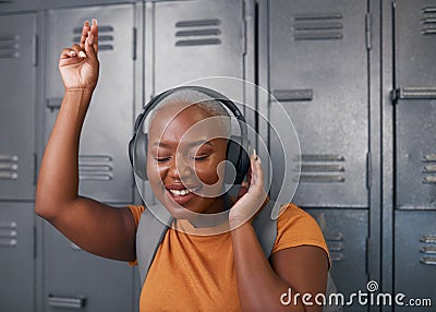 A trendy young black woman listens to music at college in front of lockers Stock Photo