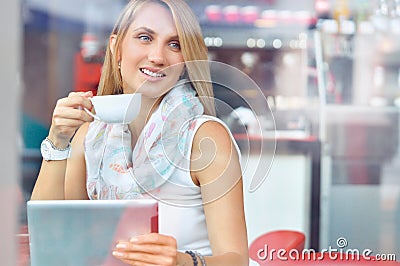 Trendy young woman in cafe with cup of coffee and touchscreen tablet Stock Photo